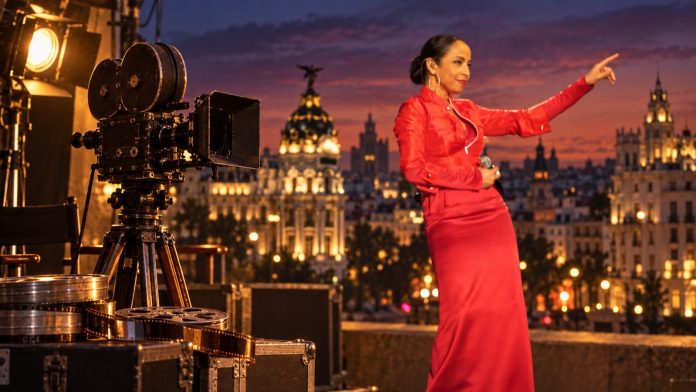 Sade Adu beside a vintage film camera against a Madrid skyline, representing Carlos Scola Pliego’s film career